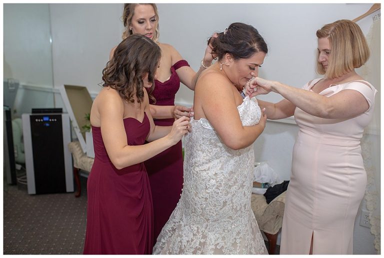 Mother of the bride helping daughter get dressed
