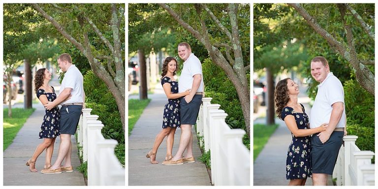 couple smiling and looking at the camera and leaning on fence